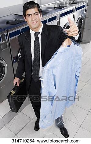 Businessman carrying a hanger in a laundromat View Large Photo Image Picture - Businessman carrying a hanger in a laundromat. Fotosearch