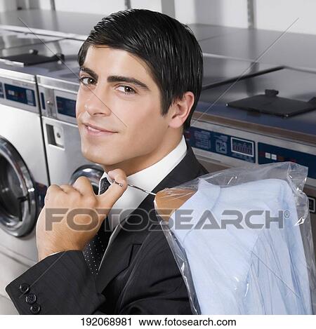 Businessman carrying a hanger in a laundromat View Large Photo Image Stock Image - Businessman carrying a hanger in a laundromat. Fotosearch