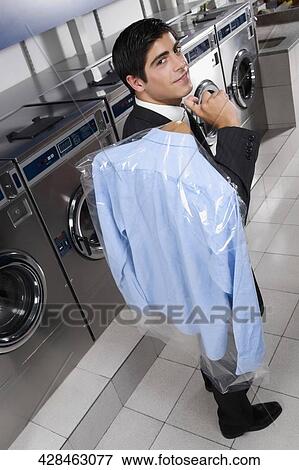 Businessman carrying a hanger in a laundromat View Large Photo Image Stock Photo - Businessman carrying a hanger in a laundromat. Fotosearch