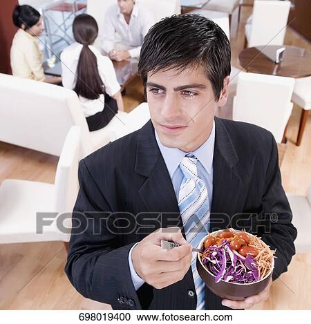 Businessman eating salad in a restaurant View Large Photo Image Stock Image - Businessman eating salad in a restaurant. Fotosearch