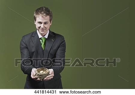 Businessman holding a golden egg in a nest View Large Photo Image Stock Image - Businessman holding a golden egg in a nest. Fotosearch