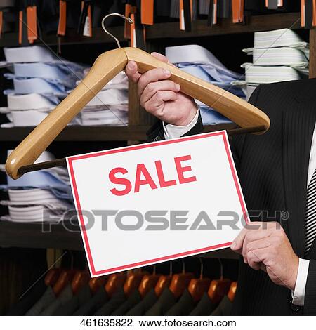 Businessman holding a Sale sign in a clothing store View Large Photo Image Stock Image - Businessman holding a Sale sign in a clothing store. Fotosearch