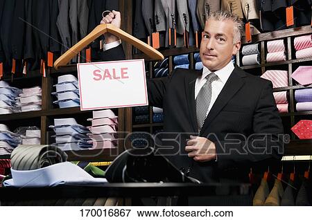 Stock Photo - Businessman holding a Sale sign in a clothing store. Fotosearch