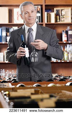 Stock Image - Businessman holding a wine bottle and a wine glass. Fotosearch