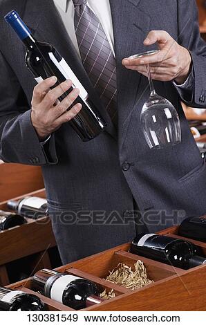 Businessman holding a wine bottle and a wine glass View Large Photo Image Stock Photo - Businessman holding a wine bottle and a wine glass. Fotosearch