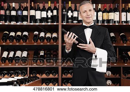 Businessman holding a wine bottle in a bar View Large Photo Image Stock Image - Businessman holding a wine bottle in a bar. Fotosearch