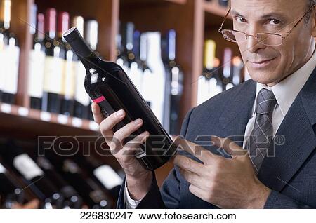 Businessman holding a wine bottle View Large Photo Image Stock Photo - Businessman holding a wine bottle. Fotosearch