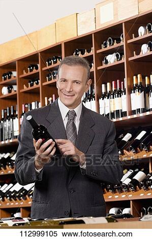 Businessman holding a wine bottle View Large Photo Image Stock Photography - Businessman holding a wine bottle. Fotosearch