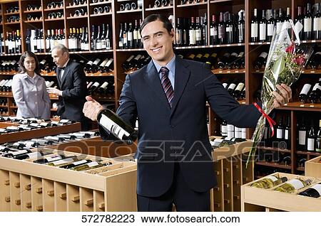 Businessman holding a wine bottle with a bouquet of flowers View Large Photo Image Stock Image - Businessman holding a wine bottle with a bouquet of flowers. Fotosearch