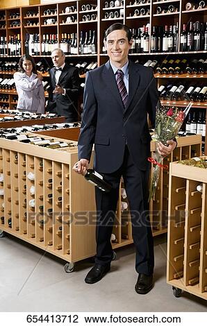 Businessman holding a wine bottle with a bouquet of flowers View Large Photo Image Stock Image - Businessman holding a wine bottle with a bouquet of flowers. Fotosearch