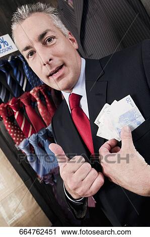 Businessman holding currency note in a clothing store View Large Photo Image Stock Image - Businessman holding currency note in a clothing store. Fotosearch