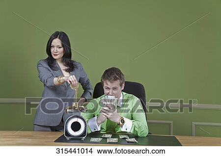 Businessman holding currency notes and a businesswoman weighing gold jewelry View Large Photo Image Picture - Businessman holding currency notes and a businesswoman weighing gold jewelry. Fotosearch