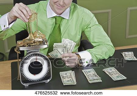 Businessman holding currency notes and weighing gold jewelry View Large Photo Image Stock Image - Businessman holding currency notes and weighing gold jewelry. Fotosearch