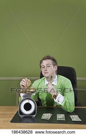Businessman holding currency notes and weighing gold jewelry View Large Photo Image Stock Photo - Businessman holding currency notes and weighing gold jewelry. Fotosearch