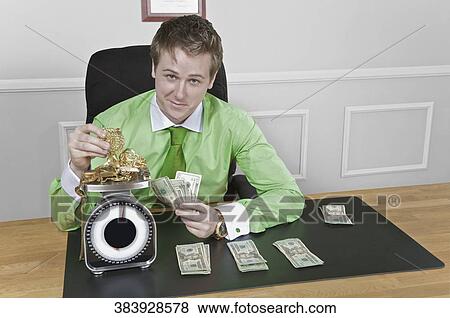 Stock Photo - Businessman holding currency notes and weighing gold jewelry. Fotosearch