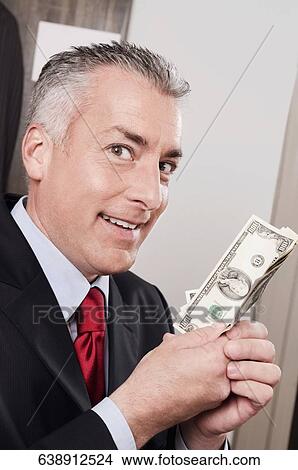 Businessman holding currency notes in a clothing store View Large Photo Image Picture - Businessman holding currency notes in a clothing store. Fotosearch