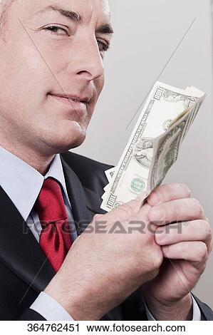 Businessman holding currency notes in a clothing store View Large Photo Image Stock Image - Businessman holding currency notes in a clothing store. Fotosearch