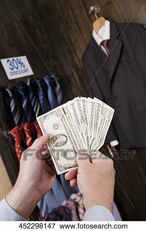 Businessman holding currency notes in a clothing store View Large Photo Image Stock Photo - Businessman holding currency notes in a clothing store. Fotosearch