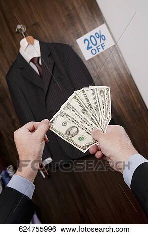 Businessman holding currency notes in a clothing store View Large Photo Image Stock Photograph - Businessman holding currency notes in a clothing store. Fotosearch