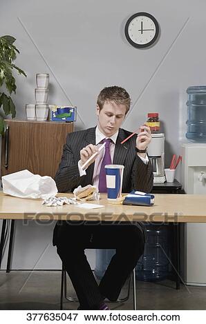 Businessman holding drinking straw in lunch break View Large Photo Image Stock Photo - Businessman holding drinking straw in lunch break. Fotosearch