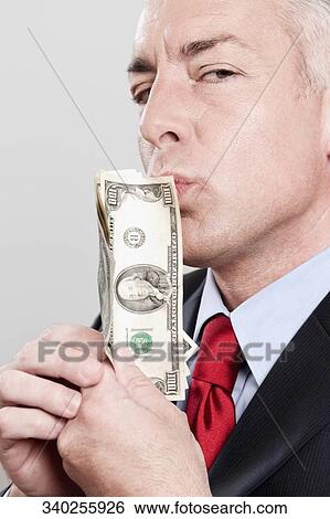 Businessman kissing currency notes in a clothing store View Large Photo Image Stock Photograph - Businessman kissing currency notes in a clothing store. Fotosearch