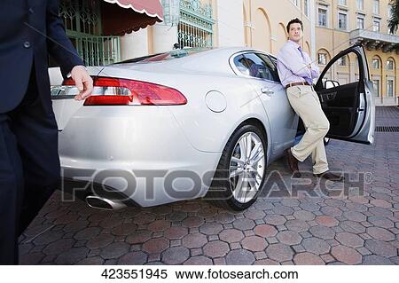 Stock Photography - Businessman leaning against a car, Biltmore Hotel, Coral Gables, Florida, USA. Fotosearch