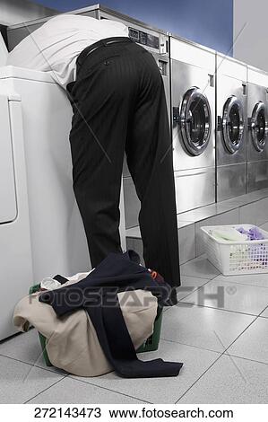 Businessman looking inside the washing machine in a laundromat View Large Photo Image Stock Image - Businessman looking inside the washing machine in a laundromat. Fotosearch