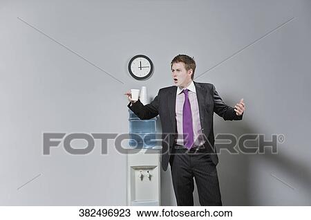 Businessman looking surprised near a water cooler View Large Photo Image Stock Image - Businessman looking surprised near a water cooler. Fotosearch