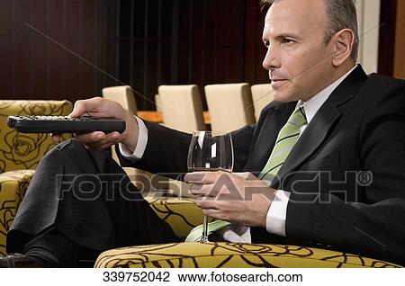 Businessman operating a remote control and holding a wine glass View Large Photo Image Stock Image - Businessman operating a remote control and holding a wine glass. Fotosearch