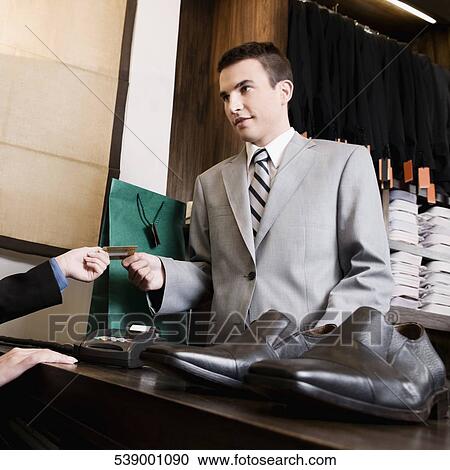 Businessman paying by a credit card in a store View Large Photo Image Stock Image - Businessman paying by a credit card in a store. Fotosearch