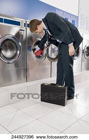 Businessman putting clothes into a washing machine View Large Photo Image Stock Photograph - Businessman putting clothes into a washing machine. Fotosearch