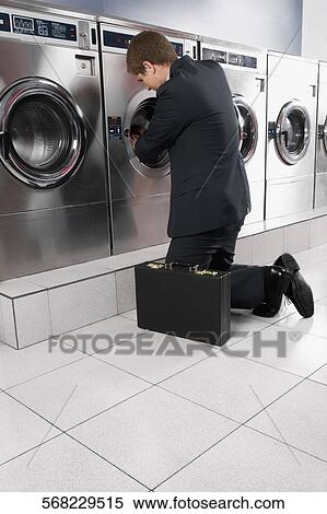 Stock Photography - Businessman putting clothes into a washing machine. Fotosearch