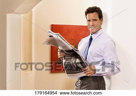 Businessman reading a newspaper and smiling View Large Photo Image Picture - Businessman reading a newspaper and smiling. Fotosearch