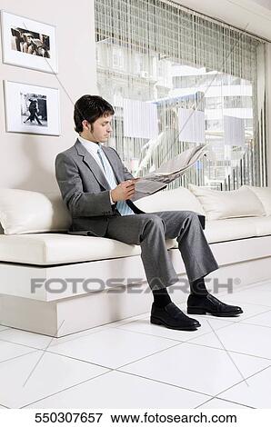 Stock Photo - Businessman reading a newspaper in a salon. Fotosearch