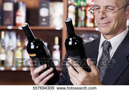 Stock Photo - Businessman reading the label of wine bottles. Fotosearch