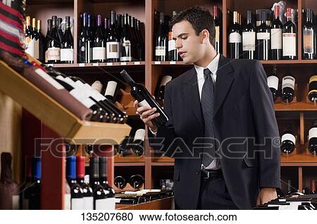 Businessman reading the label on a wine bottle View Large Photo Image Stock Image - Businessman reading the label on a wine bottle. Fotosearch
