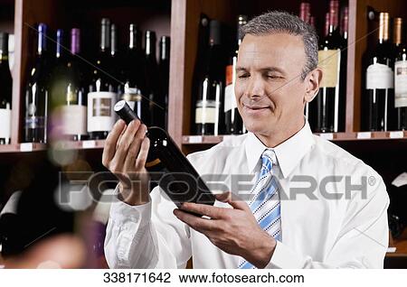 Businessman reading the label on a wine bottle View Large Photo Image Stock Image - Businessman reading the label on a wine bottle. Fotosearch