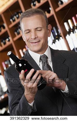 Businessman reading the label on a wine bottle View Large Photo Image Stock Photo - Businessman reading the label on a wine bottle. Fotosearch