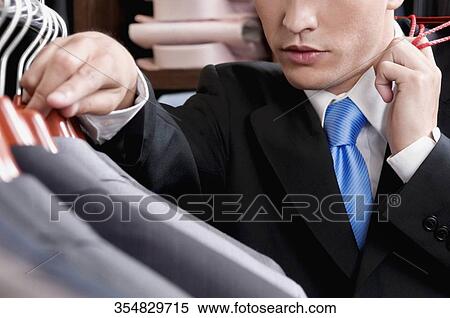 Stock Photography - Businessman selecting a suit in a clothing store. Fotosearch