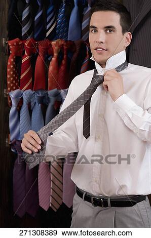 Stock Photo - Businessman selecting a tie in a clothing store. Fotosearch