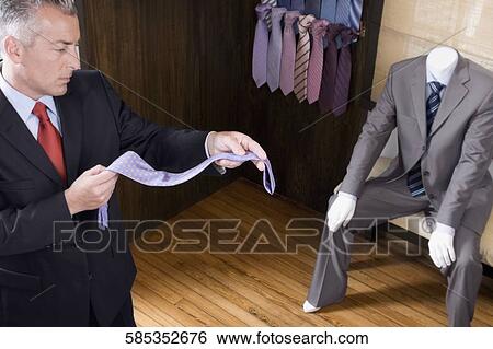 Businessman selecting a tie in a clothing store View Large Photo Image Stock Photograph - Businessman selecting a tie in a clothing store. Fotosearch