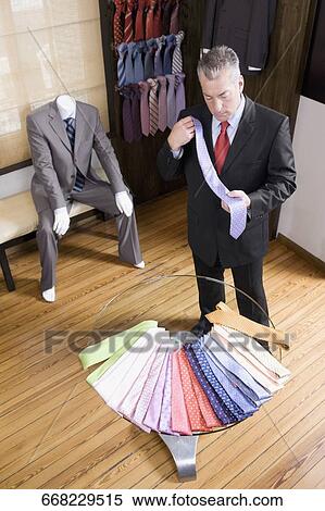 Stock Photography - Businessman selecting a tie in a clothing store. Fotosearch