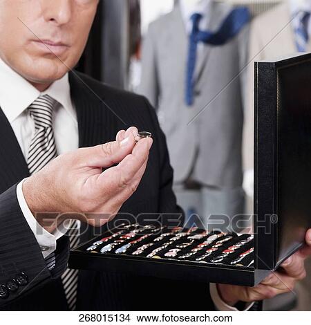 Businessman selecting cuff links in a clothing store View Large Photo Image Picture - Businessman selecting cuff links in a clothing store. Fotosearch