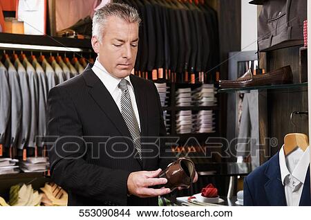 Businessman selecting shoes in a clothing store View Large Photo Image Picture - Businessman selecting shoes in a clothing store. Fotosearch