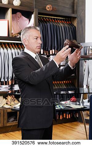Businessman selecting shoes in a clothing store View Large Photo Image Stock Photograph - Businessman selecting shoes in a clothing store. Fotosearch