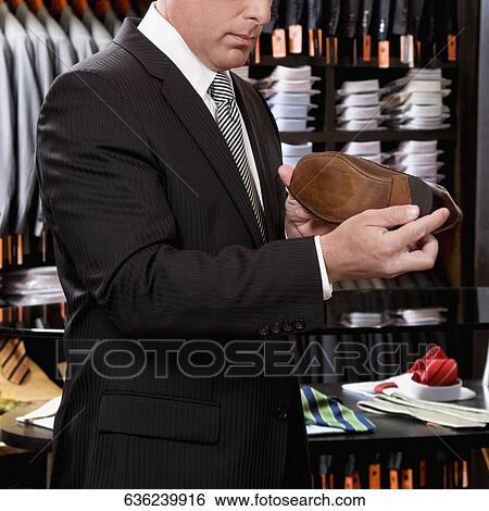 Businessman selecting shoes in a clothing store View Large Photo Image Stock Photograph - Businessman selecting shoes in a clothing store. Fotosearch