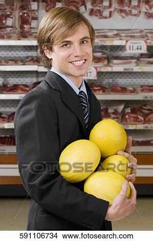 Picture - Businessman shopping canary melons in a supermarket. Fotosearch