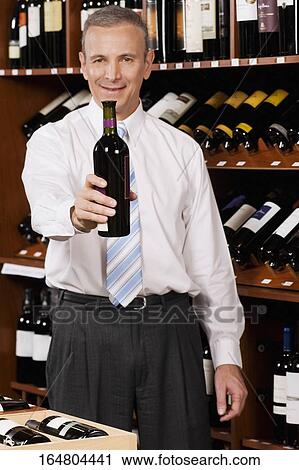 Businessman showing a wine bottle in a bar View Large Photo Image Stock Image - Businessman showing a wine bottle in a bar. Fotosearch