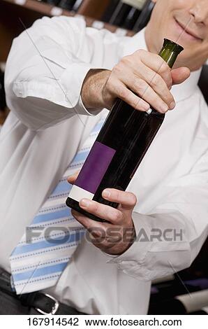 Businessman showing a wine bottle View Large Photo Image Stock Image - Businessman showing a wine bottle. Fotosearch
