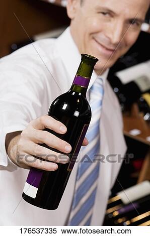 Businessman showing a wine bottle View Large Photo Image Stock Photography - Businessman showing a wine bottle. Fotosearch